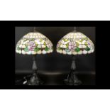 A Pair Of Reproduction Tiffany Style Table Lamps each raised on bronzed metal base with shaped