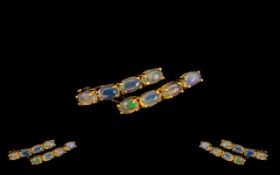 Opal J Hoop Hinge Back Earrings, each set with four oval cut, natural opal cabochons, vertically, to