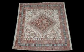 A Turkish Woven Wool Carpet with beige ground and traditional Middle Eastern red border detail