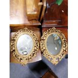 Pair of cast gilt metal oval mirrors.