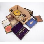 A box of assorted curios, including a bell tree, pens, and boxed games