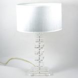 A modern table lamp, clear perspex column on a glass base, with metallic silver shade