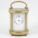 An oval brass cased carriage clock, with bevel glass panels, white enamel dial with Roman numeral