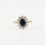 A sapphire and diamond oval cluster ring, an oval mixed cut sapphire claw set and surrounded by