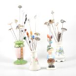 Four ceramic hat pin stands with hat pins - to include a Charles Horner citrine paste thistle in a