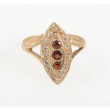 A modern 9 carat yellow gold marquise cluster ring set with three vertical garnets and a border of