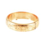 A 9 carat yellow gold 15mm wide hollow half hinged bangle, scroll decoration to front, approximate