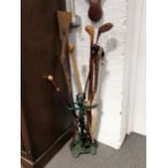 A cast-iron stickstand with sticks, golf club, etc