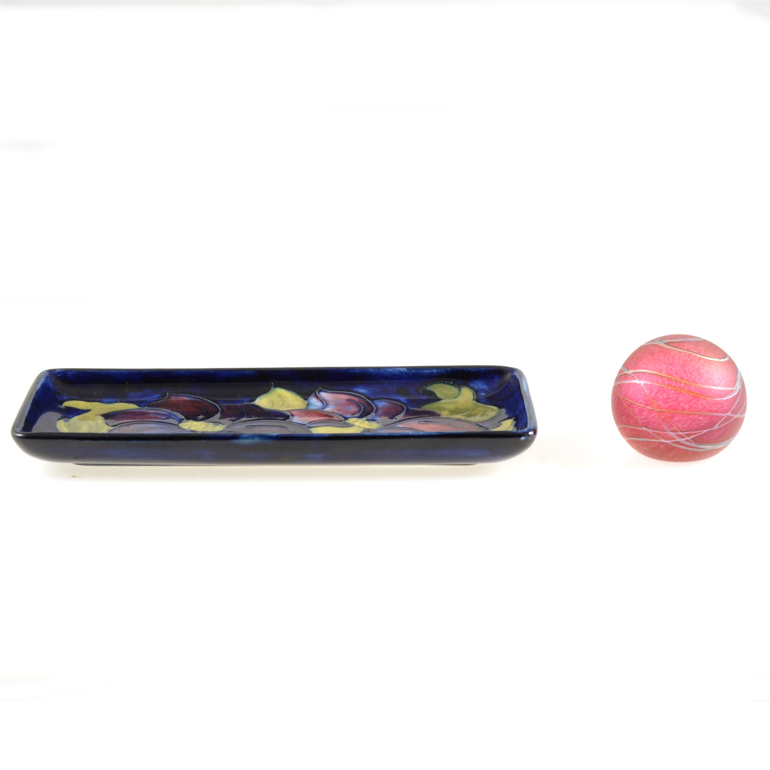 A Moorcroft Pottery pin dish, Clematis design, circa 1950; and an Okra Studio paperweight.