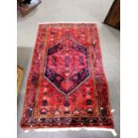 Hamadan rug, hexagonal medallion on a patterned red field, narrow border within guards, 200 x 140cm.