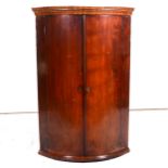 George III mahogany cylinder front hanging corner cupboard, cavetto moulded cornice, two doors