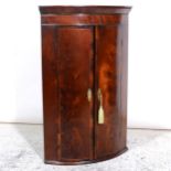 A George III mahogany bowfront hanging corner cupboard