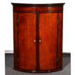 A George III oak and mahogany cylinder front hanging corner cupboard