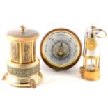 A circular modern aneroid barometer, musical cigarette dispenser, and miner's lamp.