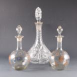 A crystal decanter with silver collar and two bulbous decanters with enamelled decoration.