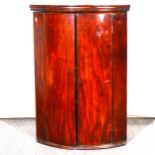 A George III mahogany cylinder front hanging corner cupboard