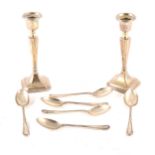 A pair of silver candlesticks and six silver teaspoons.