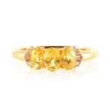 A three stone yellow sapphire ring with diamond shoulders.