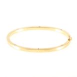 An 18 carat yellow gold half hinged bangle.