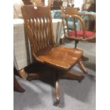 A stained wood swivel office chair,
