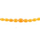A string of twenty-seven amber coloured egg shaped beads,
