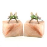 A pair of marble bookends each with a pair of cold painted bronze budgerigars