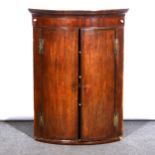 A George III oak and mahogany cylinder front hanging corner cupboard, ...