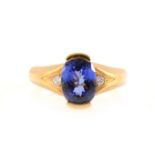 A tanzanite solitaire ring with a diamond to each shoulder.