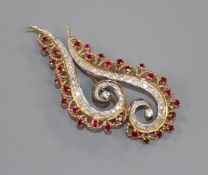 A modern yellow metal, ruby and diamond double scroll brooch, 65mm.