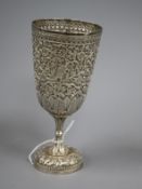 An Indian white metal pedestal cup embossed with animals amid scrolling foliage, stamped VK on the