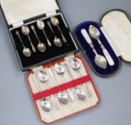 Two cased sets of silver coffee spoons and a cased pair of silver and mother of pearl butter?