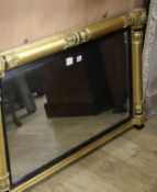 A William IV giltwood and ebonised overmantel mirror, with reeded slip flanked by foliate capped