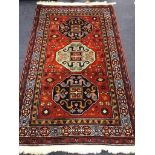 A Kazak style red ground rug, woven with three geometric medallions 204 x 127cm