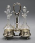 A pair of glass oil and vinegar bottles and stoppers in an Austro Hungarian white metal stand, 24.