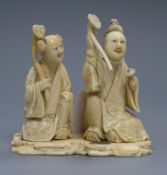 A Japanese ivory okimono of two figures holding sceptres