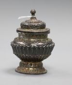 A Tibetan repousse white metal jar and cover, on detachable foot, 11.1cm.
