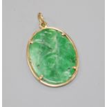 A 14ct gold and carved jadeite set oval pendant, 30mm.
