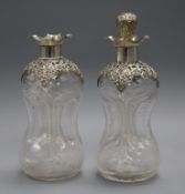 A pair of Edwardian repousse silver mounted glass waisted glug decanters and one stopper, 24.7cm