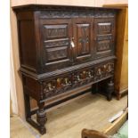 A large carved oak two door cupboard, raised on an associated oak dresser base W.170cm