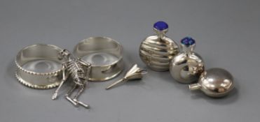 Two silver napkin rings, a skeleton charm and three silver scent flasks.