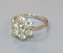 An 18ct white gold seven stone diamond cluster flower head ring, size L.