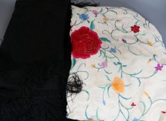 A multi-coloured embroidered shawl and black shawl