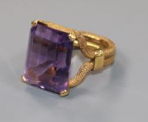 A textured yellow metal and emerald cut single stone amethyst ring, size C/D.