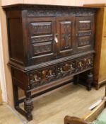 A large carved oak two door cupboard, raised on an associated oak dresser base W.170cm