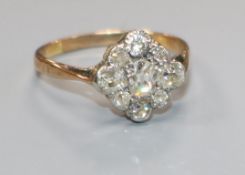 An early 20th century yellow metal and nine stone diamond cluster ring, size N.