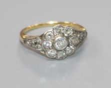 An early 20th century 18ct gold and nine stone diamond cluster ring with diamond set shoulders, size