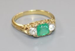 A late Victorian yellow metal, emerald and diamond three stone ring, emerald chipped, size Q.