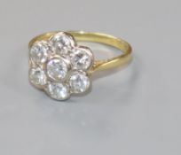 A modern 18ct gold and seven stone diamond flowerhead cluster ring, size P.