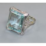 A large modern 9ct white gold and emerald cut aquamarine dress ring with diamond set shoulders, size