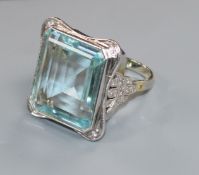 A large modern 9ct white gold and emerald cut aquamarine dress ring with diamond set shoulders, size